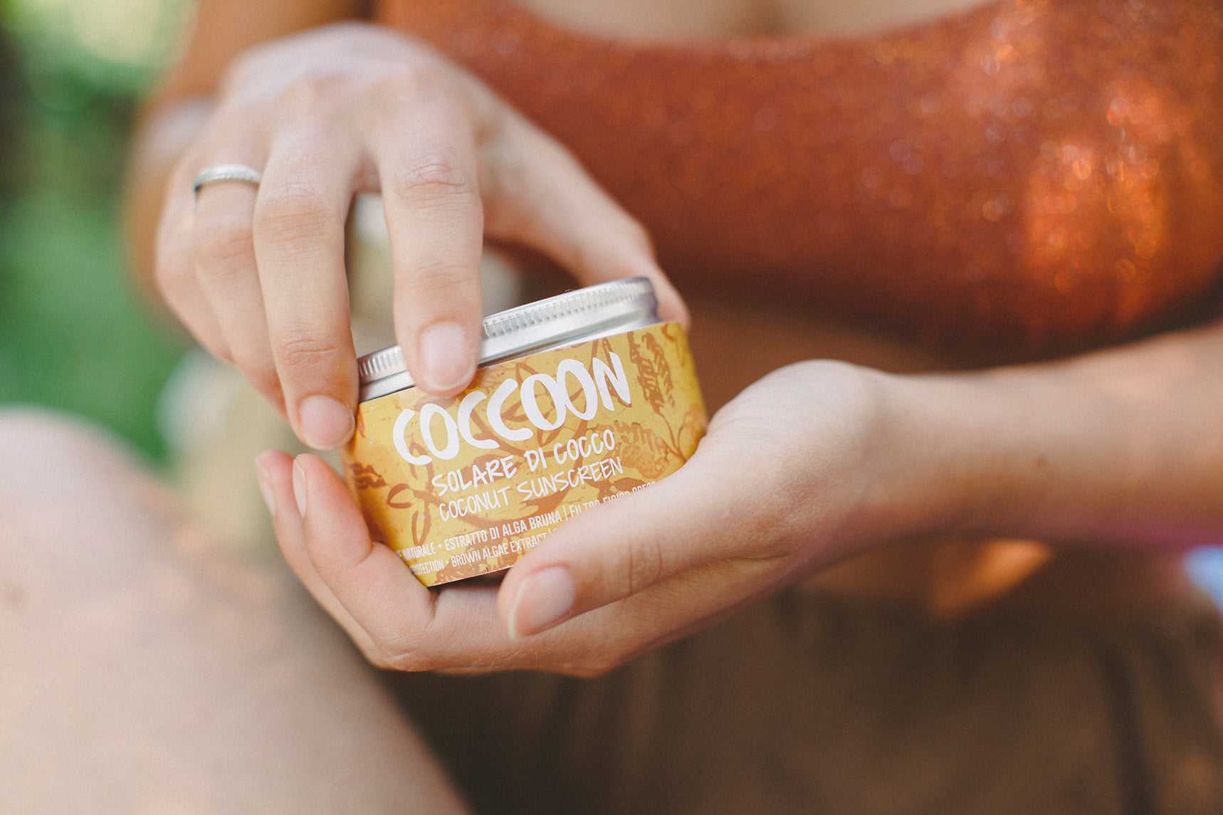 Una confezione di solare ecologico Coccoon tra le mani di una persona che lo sta per aprire.