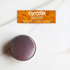 Confezione chiusa di solare di cocco Coccoon ed etichetta aperta in evidenza su un piano di marmo